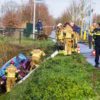 Auto op zijkant in greppel na ongeval, vrouw naar ziekenhuis